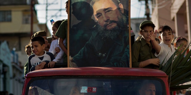 Children ride in the bed of a truck with a framed image of Fidel Castro, in Regla, Cuba, Thursday, Jan. 8, 2015.