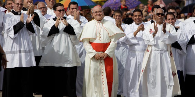 FILE - In this Sept. 4, 2011 file photo, Cuba's Cardinal Jaime Ortega, center, smiles as he waits for the Virgin of the Copper Charity during a procession in Madruga, Cuba. Ortega, who oversaw a warming of relations with the Communist government and played a role in the secret negotiations that led to U.S.-Cuba detente, has stepped down, the Vatican said on Tuesday, April 26, 2016. (AP Photo/Javier Galeano, File)