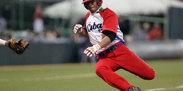 FILE - In this Feb. 7, 2015 file photo, Cuba’s Yadiel Hernandez slides safe at the home plate during a Caribbean Series baseball semifinal game against Venezuela in San Juan, Puerto Rico. Cuba is confirming that two baseball players, including Hernandez, have defected while in the United States for a series of friendly games against U.S. collegians. (AP Photo/Ricardo Arduengo, File)
