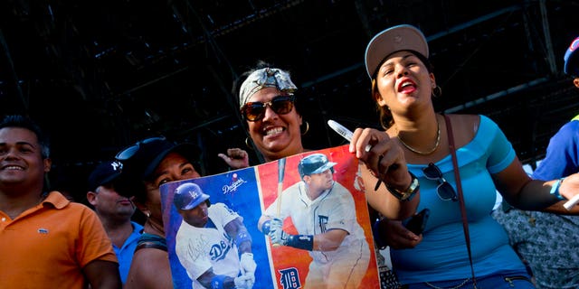 Fans hold photos of Puig and Miguel Cabrera before the players hold a baseball clinic with children in Havana in December 2015. (AP Photo/Ramon Espinosa)