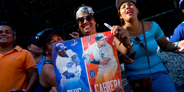 Fans hold photos of Puig and Miguel Cabrera before the players hold a baseball clinic with children in Havana in December 2015. (AP Photo/Ramon Espinosa)
