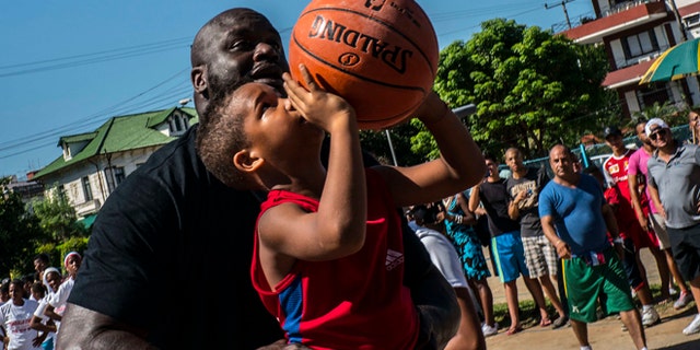 Shaquille O'Neal, plays with a youngster during a clinic with young players in Havana, Sunday, June 26, 2016.
