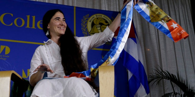Blogger and activist Yoani Sanchez, of Cuba, holds up a gift given to her in the colors of the Cuban flag before speaking at the Freedom Tower of Miami Dade College, Monday, April 1, 2013, in Miami. Sanchez has gained thousands of followers worldwide for her candid descriptions of modern life in Cuba on her blog Generation Y. (AP Photo/Lynne Sladky)
