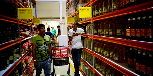 Shoppers walk through the aisles of a new bulk goods store in Havana, Cuba, Monday, July 11, 2016. Called Zona +, the high-ceiling space has racks stacked with large tins of tomato sauce, toilet paper and cooking oil by the gallon. (AP Photo/Ramon Espinosa)