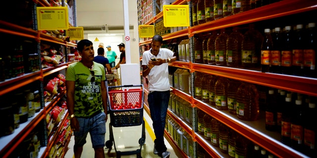 Shoppers walk through the aisles of a new bulk goods store in Havana, Cuba, Monday, July 11, 2016. Called Zona +, the high-ceiling space has racks stacked with large tins of tomato sauce, toilet paper and cooking oil by the gallon. (AP Photo/Ramon Espinosa)