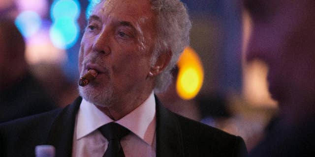 Welsh crooner Tom Jones smokes a cigar during a gala dinner marking the end of the 16th annual Cigar Festival in Havana, Cuba, Friday, Feb. 28, 2014. The festival is a five-day bash that brings together hundreds of cigar sophisticates from around the world, and culminates with a gala and auction of humidors worth hundreds of thousands of dollars. Tom Jones was among the celebrity invitees at Saturday's auction and sang three songs for attending guests, including his signature "It's Not Unusual."(AP Photo/Franklin Reyes)