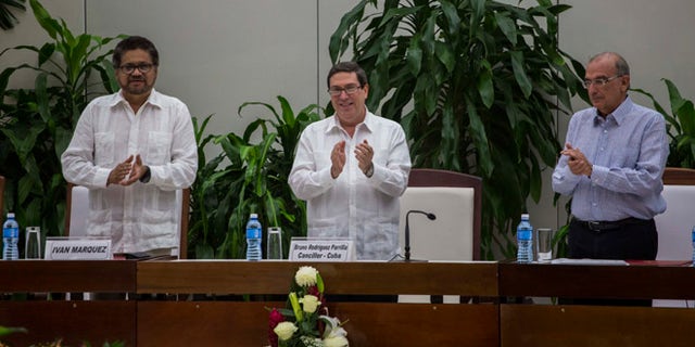 Ivan Marquez, chief negotiator of the Revolutionary Armed Forces of Colombia, or FARC, from left, Cuba's Foreign Minister Bruno Rodriguez, and Humberto de La Calle, head of Colombia's government peace negotiation team, applaud after the signing of the latest text of the peace accord between the two sides in Havana, Cuba, Saturday, Nov. 12, 2016. Colombia's government and the FARC signed a new, modified peace accord on Saturday following the surprise rejection of an earlier deal by voters in a referendum. (AP Photo/Desmond Boylan)