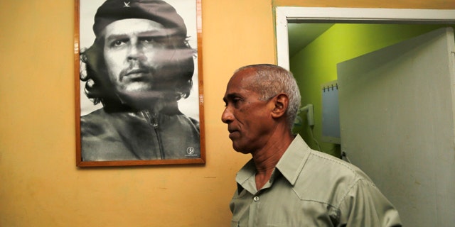 April 19, 2015: Dissident and candidate Hildebrando Chaviano walks beside a portrait of revolutionary leader Che Guevara before casting his ballot during Cuba's municipal elections at a polling station in Havana. (AP Photo/Desmond Boylan)
