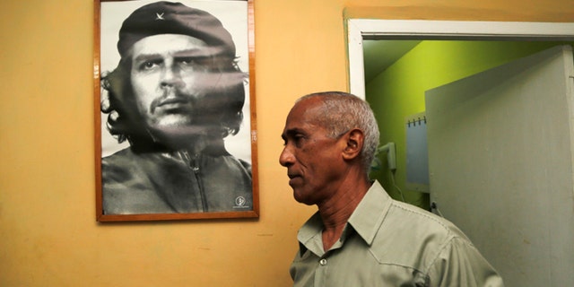 Dissident and candidate Hildebrando Chaviano walks beside a portrait of revolutionary leader Che Guevara before casting his ballot during Cuba's municipal elections at a polling station in Havana, Cuba, Sunday, April 19, 2015. Cuba held its first local elections since a historic thaw in relations with the United States with an unusual wrinkle in the single-party system: two of the 27,000 candidates openly oppose the government. (AP Photo/Desmond Boylan)