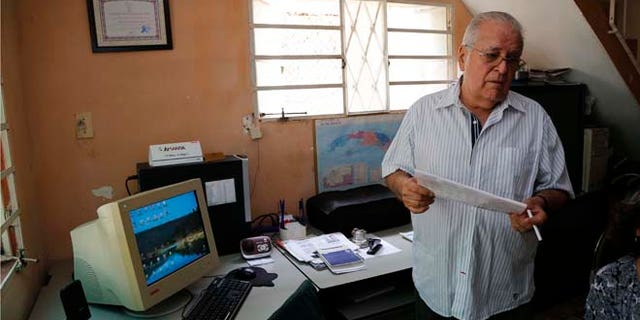 In this July 2, 2015 photo, dissident Elizardo Sanchez, president of the Cuban Commission for Human Rights and National Reconciliation, stands in his home in Havana, Cuba. Many of the dissidents are feeling increasingly sidelined and abandoned as both countries celebrate milestones like Monday's opening of embassies in Havana and Washington. (AP Photo/Desmond Boylan)