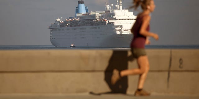 FILE - In this March 19, 2015, file photo, a woman jogs on the Malecon as the Thomson Dream cruise ship arrives in Havana bay. The Obama administration has approved on Tuesday, May 5, 2015, the first ferry service in decades between the United States and Cuba, potentially opening a new path for the hundreds of thousands of people and hundreds of millions of dollars in consumer goods that travel between Florida and Havana each year. (AP Photo/Desmond Boylan, File)