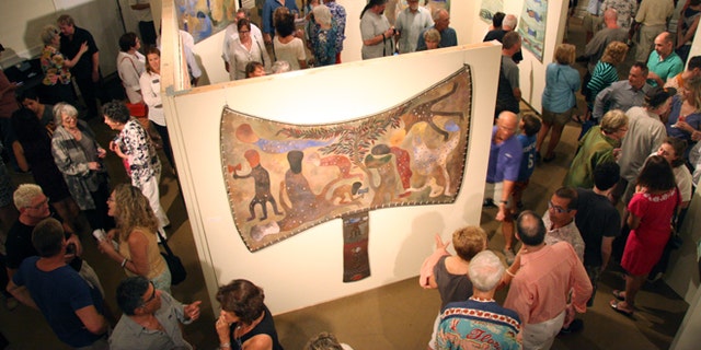 In this Thursday, Feb. 20, 2014 photo, patrons look at work by Cuban artist Manuel Mendive at the Studios of Key West in Key West, Fla. Mendive's work is on display as part of an exhibit that organizers say is the first exchange between Cuban and U.S. art museums in more than five decades. (AP Photo/Christine Armario)