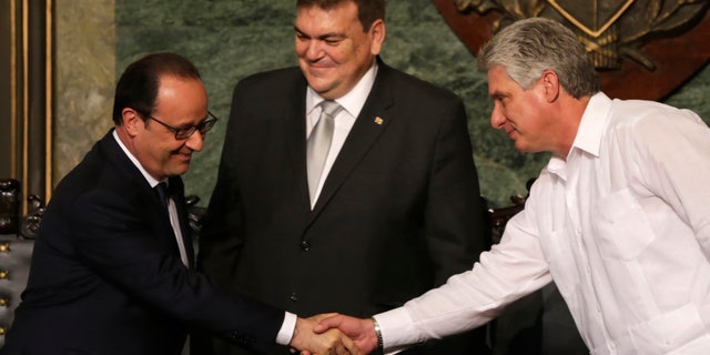 French President Francois Hollande shakes hands with Cuba's Vice President Miguel Diaz-Canel, right, in front of Gustavo Cobreiro, University Havana rector, in Havana, Cuba, Monday, May 11, 2015. Accompanied by a group of top French business people, Hollande has become the first French president to visit Cuba since it became an independent country, using a one-day trip to build business and diplomatic relations five months after a detente between Havana and Washington.(AP Photo/Desmond Boylan)