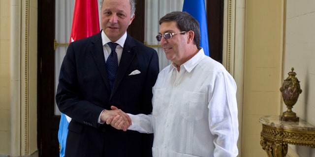April 12, 2014: Cuba's Foreign Minister Bruno Rodriguez, right, and France's Foreign Minister Laurent Fabius shake hands toward photographers prior to their meeting at the Foreign Ministry in Havana, Cuba. (AP Photo/Ramon Espinosa)