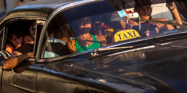 A taxi driver transports a car full of passengers, in Havana, Cuba, Tuesday, Feb. 17, 2015. A more relaxed and hopeful atmosphere is evident in Cuba as a result of President Raul Castroís modest reforms and afte the agreement by Cuba and the U.S. to move toward a more normal relationship. (AP Photo/Ramon Espinosa)