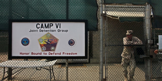 FILE - In this file photo taken Tuesday May 12, 2009 and reviewed by the U.S. military, a soldier stands guard at the front gate entrance to Guantanamo's Camp 6 maximum-security detention facility, at Guantanamo Bay U.S. Naval Base, Cuba. The U.S. government said Sunday Dec. 7, 2014 six men who have been held more than 12 years at Guantanamo Bay have been sent to Uruguay to be resettled as refugees. (AP Photo/Brennan Linsley, File)