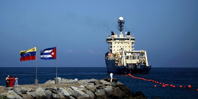 Jan. 22, 2011: {eople stand on a breakwater, with a Venezuelan flag, left, and a Cuban flag, as a specialized ship rolls out a fiber-optic cable, suspended from buoys, off La Guaira, Venezuelan coast. Cuba's state telecom monopoly confirmed Thursday, Jan. 24, 2013 that the island's first hard-wired Internet connection to the outside world has been activated, but said it won't lead to an immediate increase in access.