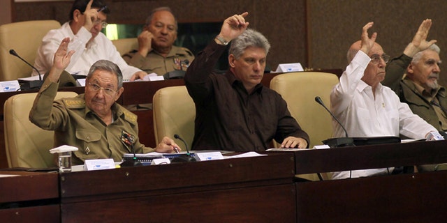 Cuba'ss Vice-President Miguel Díaz-Canel, center, Cub's President Raúl Castro, left, First Vice-President of the Council of State José Ramón Machado Ventura, second from right, and Commander of the Cuban Revolution Ramiro Valdes, right, raise their hands to vote the foreign investment law during an extraordinary session at the National Assembly in Havana, Cuba, Saturday, March. 29, 2014. Cuban lawmakers approved a law Saturday that aims to make it more attractive for foreign investors to do business in and with the country, a measure seen as vital if the island's struggling economy is to improve. IN the back row, also voting, Foreign Minster Bruno Rodrigues, left, and Defense Minister Leopoldo Cintas Frias, right. (AP Photo/Ismael Francisco, Cubadebate)