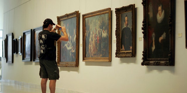 HAVANA - DECEMBER 01: A visitor photographs the paintings on display at the Fine Arts Museum December 1, 2006 in Havana, Cuba. (Photo by Joe Raedle/Getty Images)