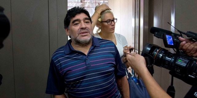 Argentina's soccer legend Diego Armando Maradona talks to journalists at the airport on his way to catch a departing plane in Havana, Cuba, Monday, Jan. 12, 2015. Behind is his girlfriend Rocio Oliva. Fidel Castro on Monday sent Maradona a letter written to quash rumors of the Cuban leader's death, state-run television network Telesur reported. It was the first reported word from Castro in nearly three months. The network showed photos of Maradona with the letter signed by Castro, 88. Telesur revealed nothing about the contents of the letter, but said it rebutted rumors he had died. (AP Photo/Ramon Espinosa)