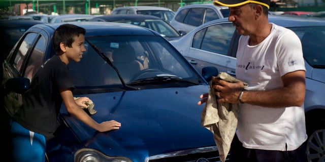 Jan. 2, 2014: A car dealership worker, right, and a boy clean a used Chinese Geely for sale at a government-run dealership in Havana, Cuba.