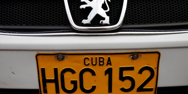 FILE - This Dec. 19, 2013 file photo shows a detail of a license plate on a Peugeot as it drives by in Havana, Cuba. Cuban authorities reported on Monday, June 30, 2014 that auto dealerships have sold just 50 automobiles and four motorcycles across the country in the nearly six months since a new law took effect letting islanders buy vehicles without a special permit for the first time in decades. Many Cubans were delighted when the new rules were announced in December 2013, and then left aghast by the sticker prices once they took effect. Most Cubans earn about $20 a month. (AP Photo/Franklin Reyes, File)