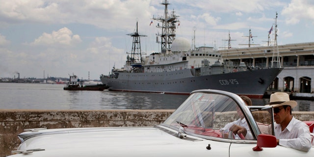 An American classic car passes in front of the Russian warship The Viktor Leonov CCB-175 docked in Havana's harbor in Havana, Cuba, Thursday, Feb. 27, 2014. A Russian warship, one of the fleets Vishnya-class ships which are generally used for intelligence gathering was docked in the Havana harbor on Thursday, a day after the country's defense minister announced plans to expand Russia's worldwide military presence. (AP Photo/Franklin Reyes)