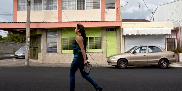 July 9, 2014: A woman walks in front of the building that once housed the human rights group Fundacion Operacion Gaya Internacional in Heredia, Costa Rica. (AP Photo/Esteban Felix)