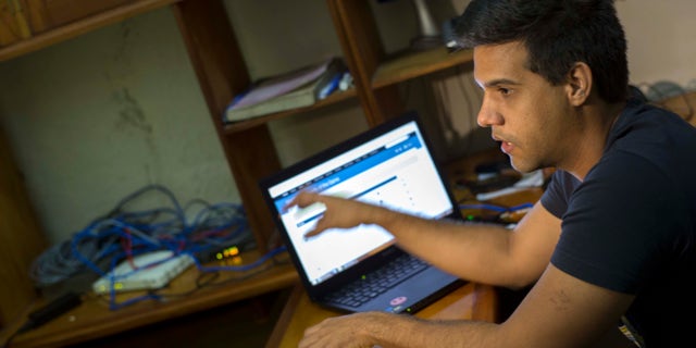 In this Jan. 4, 2015 photo, Rafael Antonio Broche Moreno talks during an interview with The Associated Press, next to his computer, modem and intranet network cabling at his home in Havana. Disconnected from the real Internet, the intranet network is limited, local and built with equipment commercially available around the world, with no help from any outside government, organizers say. (AP Photo/Ramon Espinosa)
