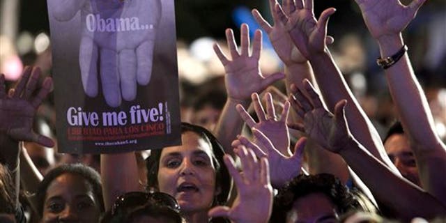 A woman holds a poster that reads "Obama give me five" during a concert in honor of the five intelligence agents in Havana, Cuba, Saturday, March 1, 2014. Thousands of Cubans rallied at the University of Havana on Saturday night for a concert to give a hero's welcome to the second of five intelligence agents to return to the island after completing long prison terms in the United States. (AP Photo/Franklin Reyes)