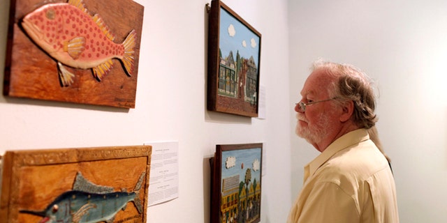 A man looks at art by Mario Sanchez, a deceased Florida artist of Cuban descent, inside the Bellas Artes museum in Havana, Cuba, late Friday, Jan. 17, 2014. The show, titled "Una Raza" or "One Race," is part of an exchange between Havana and Key West under which several prominent Cuban artists will exhibit on the Florida island next month. (AP Photo/Franklin Reyes)
