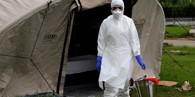 In this Sept. 24, 2014 photo, nurse Dalila Martinez, trainer of the Cuban medical team to travel to Sierra Leone, practices proper disposal at a training camp, in Havana, Cuba. Cuba's health ministry is sending more than 160 health workers to help stop the raging Ebola outbreak in Sierra Leone in early October. They will stay for six months. (AP Photo/Ladyrene Perez, Cubadebate)