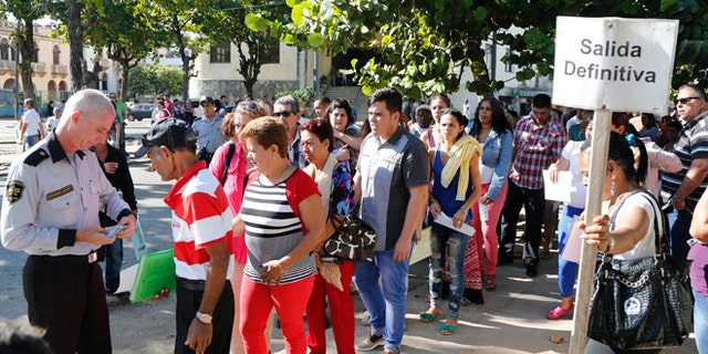 People queue for visas at the U.S. Interests Section in Havana, Cuba, Monday, Dec. 22, 2014. After the surprise announcement of the restoration of diplomatic ties between Cuba and the U.S., many Cubans expressed hope that it will mean greater access to jobs and the comforts taken for granted elsewhere, and lift their struggling economy. The sign on the post reads in Spanish "definite Exit." (AP Photo/Desmond Boylan)