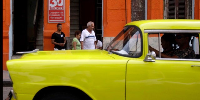 A classic American car that is used as a taxi passes by the entrance of a private movie theater called "3D Mania" in Havana, Cuba, Monday, Oct. 28, 2013. Cuban entrepreneurs have quietly opened dozens of backroom video salons over the last year, seizing on ambiguities in licensing laws to transform cafes and childrenâs entertainment parlors into a new breed of private business unforeseen by recent official openings in the communist economy. (AP Photo/Franklin Reyes)