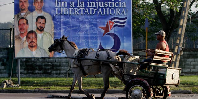 A driver guides his horse drawn carriage past a billboard demanding the freedom of five Cuban intelligence agents imprisoned in U.S., popularly known as the "Cuban Five," in Havana, Cuba.