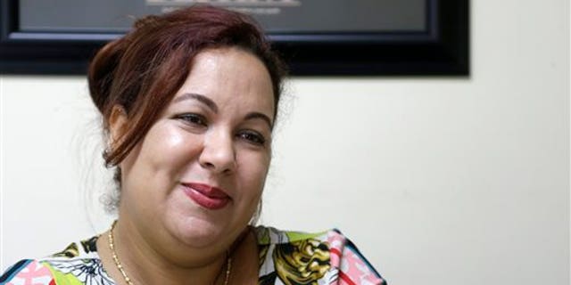 In this Sept. 19, 2013 photo, Irka Ducasse Blanes, a recent Cuban immigrant, smiles during an interview at a tax preparation office where she works in Miami. Since 2002, the number of Cubans leaving has hovered around 30,000 annually, making the last 10 years the largest exodus since the start of the revolution. The influx of new arrivals is evident throughout Miami, the heart of Cubas exile population. (AP Photo/Wilfredo Lee)