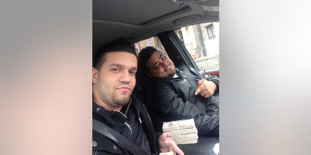 May 9, 2013: In this undated photo provided by the United States Attorneys Office for the Southern District of New York, Elvis Rafael Rodriguez, left, and Emir Yasser Yeje, pose with bundles of cash allegedly stolen using bogus magnetic swipe cards at cash machines throughout New York.