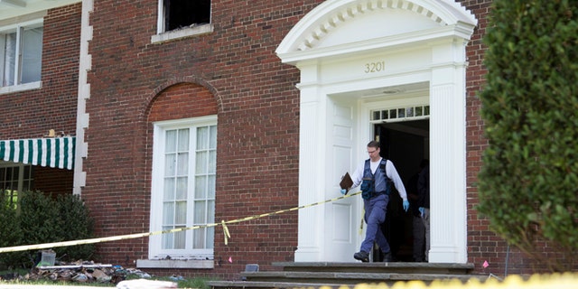 A Bureau of Alcohol, Tobacco, Firearms and Explosives investigator walks out of the fire-damaged multimillion-dollar home in northwest Washington, Wednesday, May 20, 2015, where four people were found dead May 14. Police issued a news release late Wednesday saying they are looking for a man identified as Daron Dylon Wint in connection with last Thursday's quadruple homicide. (AP Photo/Manuel Balce Ceneta)