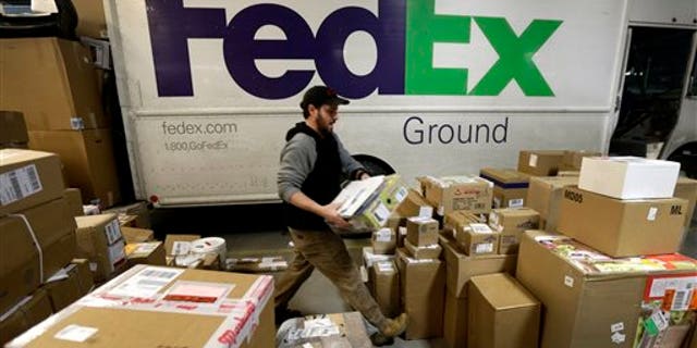 FILE - In this Dec. 16, 2013 file photo, package handler Chris Addison arranges packages before loading a delivery truck at a FedEx sorting facility in Kansas City, Mo. Santa's sleigh didn't make it in time for Christmas for some this year due to shipping problems at UPS and FedEx.The delays were blamed on poor weather earlier this week in parts of the country as well as overloaded systems. (AP Photo/Charlie Riedel)