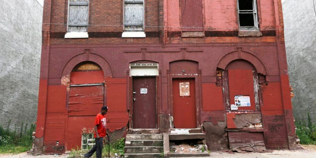 FILE - In this July 11, 2013 file photo a man walks through a blighted neighborhood in Philadelphia. Democrats are set to begin their convention Monday, July 25, 2016, in a city that symbolizes both the nation's promise and its shortcomings. (AP Photo/Matt Rourke, File)