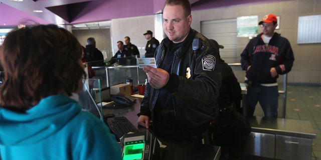 NOGALES, AZ - FEBRUARY 26: Officer Joe Sokolowski from the Office of Field Operations (OFO) checks identifications at a port of entry from Mexico into the United States on February 26, 2013 in Nogales, Arizona. Some 15,000 people cross between Mexico and the U.S. each day in Nogales, Arizona's busiest border crossing. (Photo by John Moore/Getty Images)