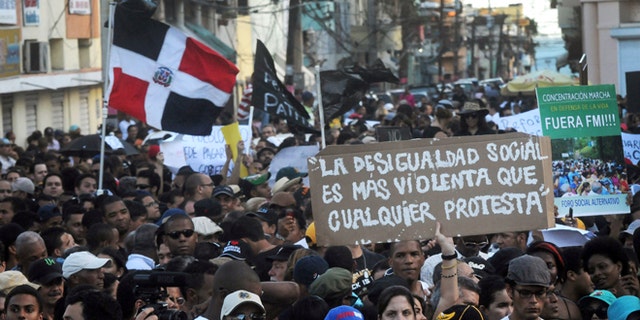 Dominicans attend a demonstration against the fiscal reform in Santo Domingo, Dominican Republic, Sunday, Nov. 11, 2012. Hundreds of Dominicans protested against the government of Danilo Medina who presented to Congress the disputed tax legislation as a way to help close the $4.6 billion deficit in the government's budget. The measure will increase the general sales tax to 18 percent from 16 percent, will raise the price of gasoline and impose taxes on basic food products. The sign reads in Spanish: "Social inequality is more violent than any protest". (AP Photo/Manuel Diaz)