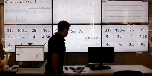 Sept. 9, 2015: An employee in the software development department of DraftKings, a daily fantasy sports company, walks past screens displaying the company's online system stats in Boston. (AP Photo/Stephan Savoia)