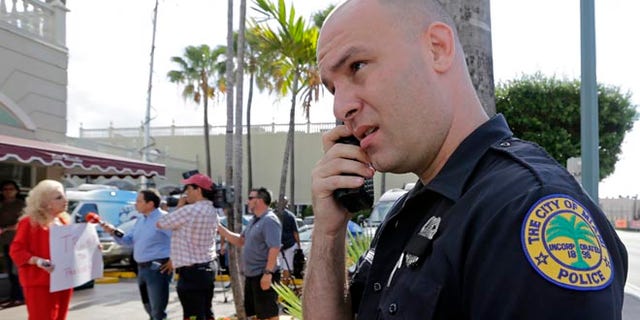 City of Miami police officer R. Delgado covers his badge with a black band as he honors the death of police officers in Dallas, Friday, July 8, 2016, at a Republican presidential candidate Donald Trump campaign stop. Trump has called off his two Friday campaign events in Miami in the wake of deadly sniper killings of Dallas police officers. (AP Photo/Alan Diaz)