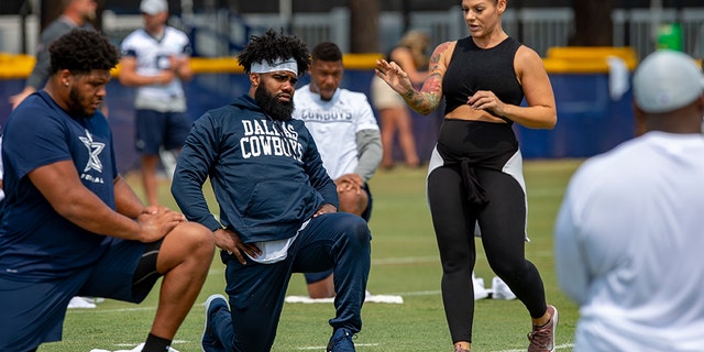 FILE - In this July 28, 2018, file photo, Dallas Cowboys offensive tackle La'el Collins, left and running back Ezekiel Elliott, center, listen to yoga instructor Stacey Hickman, right, as the team does some flexibility exercises at NFL football training camp in Oxnard, Calif. (AP Photo/Gus Ruelas, File)