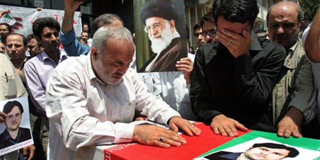 July 24: Relatives and friends mourn over the coffin of Darioush Rezaeinejad, shown in the picture on the coffin, in a funeral ceremony in Tehran, Iran, who was killed in a deadly shooting on Saturday.