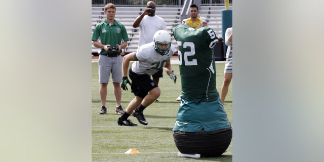 Dartmouth College Engineering graduate Quinn Connell, upper left, controls the movement of the team's Mobile Virtual Player during college football practice Wednesday Aug. 26, 2015.