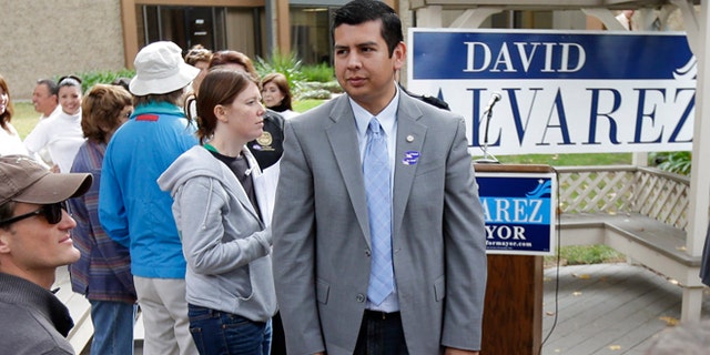 David Alvarez, above center, a San Diego city councilman and Democratic candidate for mayor, looks on as he meets with supporters Tuesday, Nov. 19, 2013, in San Diego. San Diegans head to the polls Tuesday to choose a new mayor, after Bob Filner's resignation amid allegations of sexual harassment has left the city with an interim mayor. (AP Photo/Gregory Bull)