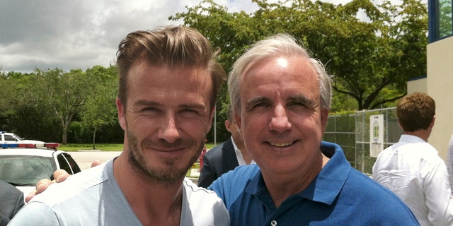 In this undated photo released by Miami-Dade County, former soccer star David Beckham poses for a photo with Miami-Dade County Mayor Carlos Gimenez, in Miami. Beckham may be setting his sights on a new sports venture: A professional soccer team in Miami. The newly retired Beckham toured Sun Life and Florida International University stadiums and met with Miami-Dade County Mayor Carlos Gimenez on Saturday. (AP Photo/Miami-Dade County)