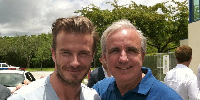 In this undated photo released by Miami-Dade County, former soccer star David Beckham poses for a photo with Miami-Dade County Mayor Carlos Gimenez, in Miami. Beckham may be setting his sights on a new sports venture: A professional soccer team in Miami. The newly retired Beckham toured Sun Life and Florida International University stadiums and met with Miami-Dade County Mayor Carlos Gimenez on Saturday. (AP Photo/Miami-Dade County)